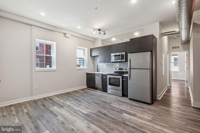 kitchen with rail lighting, backsplash, light hardwood / wood-style floors, and stainless steel appliances