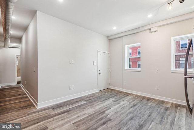 empty room featuring rail lighting and hardwood / wood-style flooring