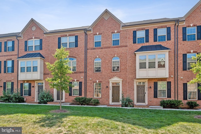 townhome / multi-family property with brick siding and a front lawn