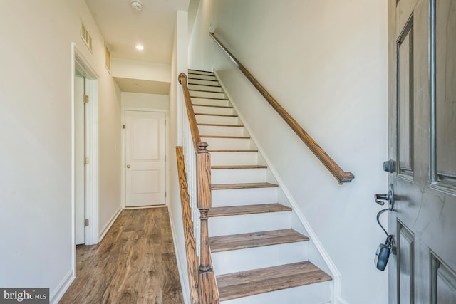 staircase with wood finished floors, visible vents, and baseboards