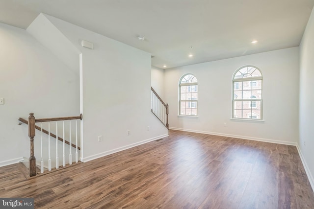 spare room with baseboards, stairway, wood finished floors, and recessed lighting