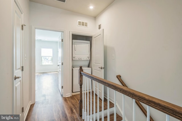 corridor featuring an upstairs landing, baseboards, visible vents, stacked washer / drying machine, and dark wood finished floors