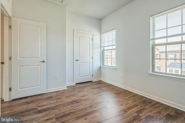 unfurnished bedroom with dark wood-style flooring and baseboards