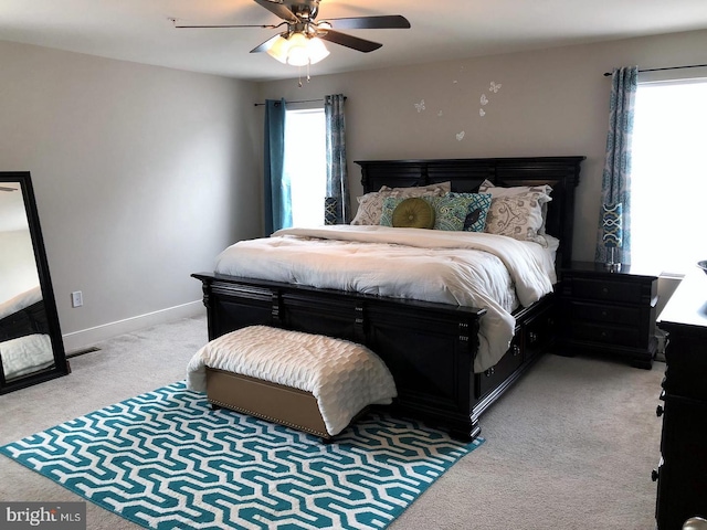 carpeted bedroom with multiple windows and ceiling fan