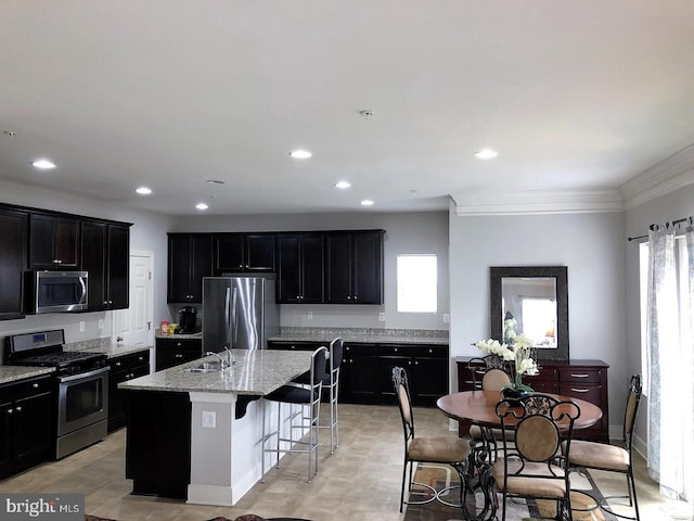 kitchen featuring a breakfast bar, appliances with stainless steel finishes, plenty of natural light, and a kitchen island with sink