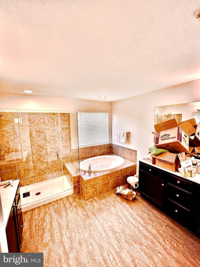 bathroom featuring a textured ceiling, vanity, shower with separate bathtub, and hardwood / wood-style flooring