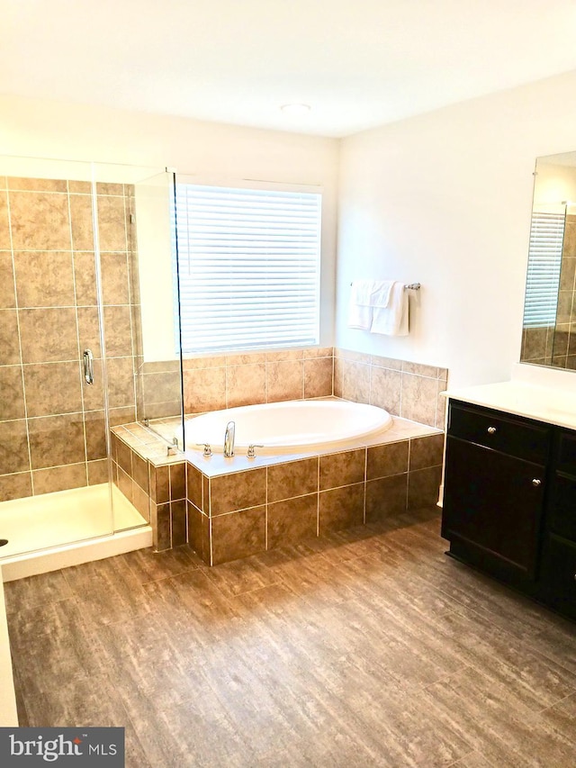 bathroom with hardwood / wood-style flooring, vanity, and shower with separate bathtub