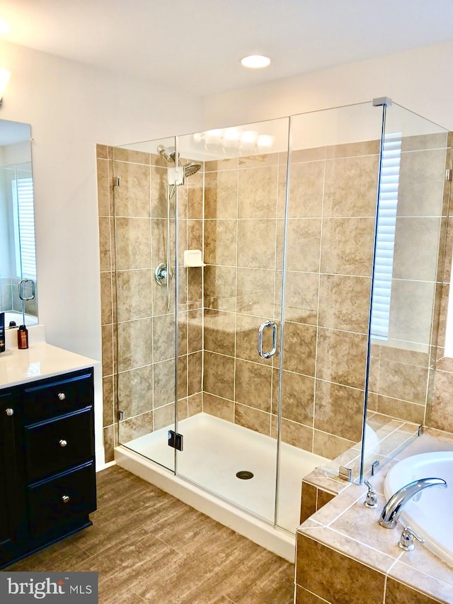 bathroom with hardwood / wood-style flooring, vanity, and independent shower and bath