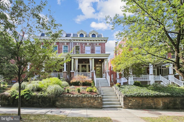 view of front of property with stairway, a porch, a high end roof, mansard roof, and brick siding