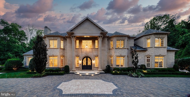 view of front facade featuring french doors, brick siding, and a chimney