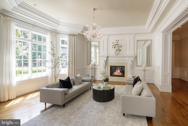 sitting room with ornamental molding, wood finished floors, a fireplace, a decorative wall, and a notable chandelier