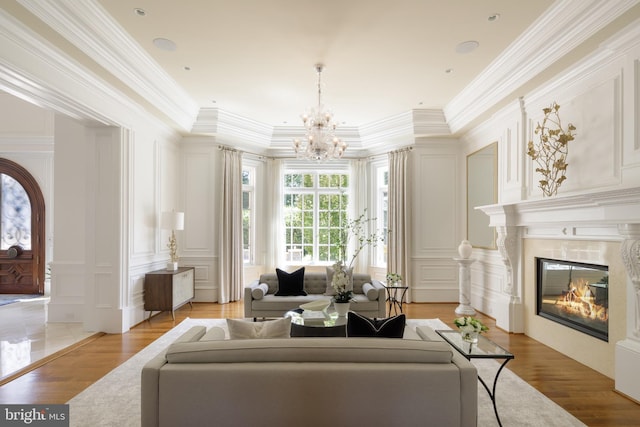 living room featuring light wood-style floors, a premium fireplace, ornamental molding, and a decorative wall