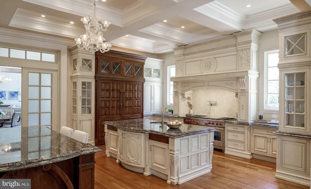 kitchen with cream cabinetry, stainless steel range, wood finished floors, and an inviting chandelier