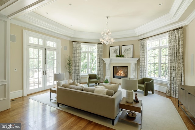 living area featuring wood finished floors, french doors, a glass covered fireplace, and ornamental molding