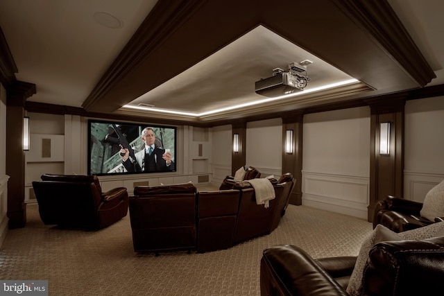 carpeted cinema with crown molding, a raised ceiling, and a decorative wall