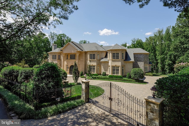 view of front of house featuring stone siding, a fenced front yard, a chimney, and a gate