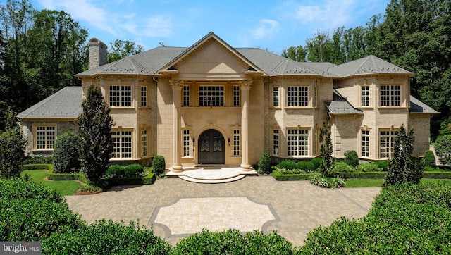 view of front of property featuring stone siding, brick siding, and a chimney