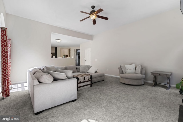 living area featuring carpet floors, baseboards, and a ceiling fan