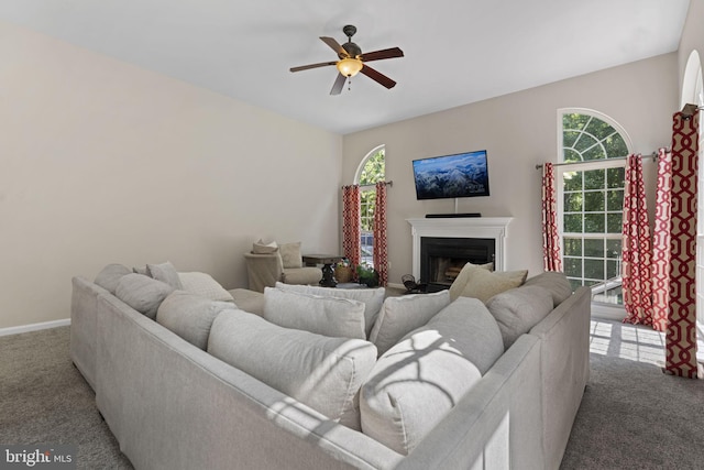 carpeted living area with a fireplace, baseboards, and a ceiling fan