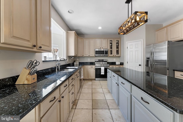 kitchen with light tile patterned flooring, dark stone counters, sink, decorative light fixtures, and appliances with stainless steel finishes