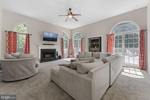 living room featuring light carpet, ceiling fan, and a fireplace with flush hearth