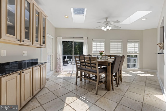 tiled dining area with ceiling fan and a skylight