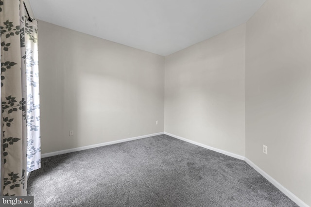 empty room with baseboards and dark colored carpet