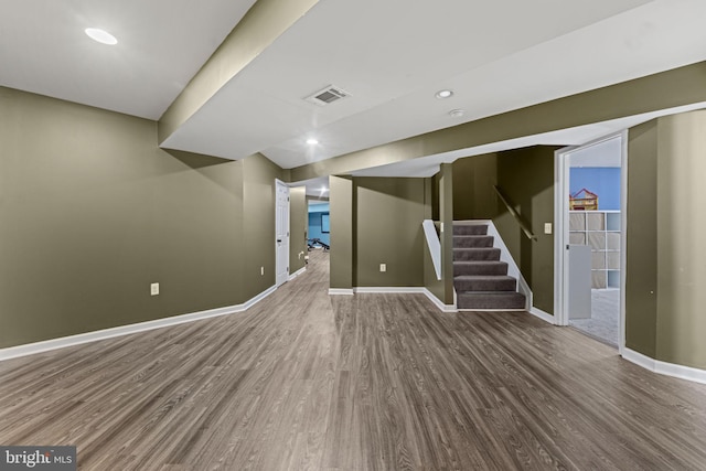 finished basement featuring recessed lighting, visible vents, wood finished floors, baseboards, and stairs