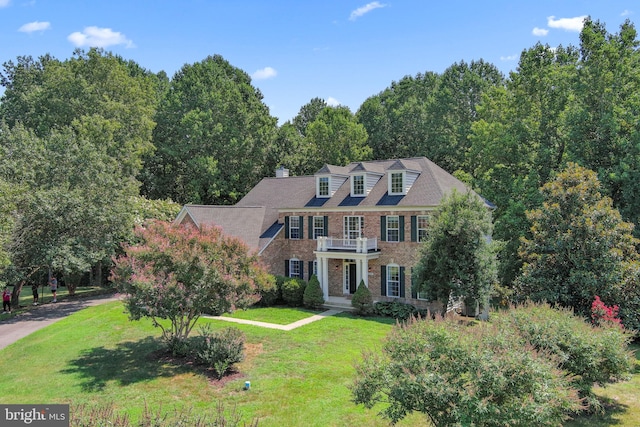 colonial house featuring brick siding and a front yard