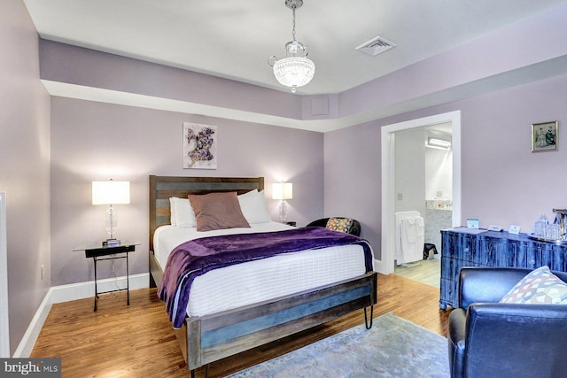 bedroom featuring an inviting chandelier and light wood-type flooring