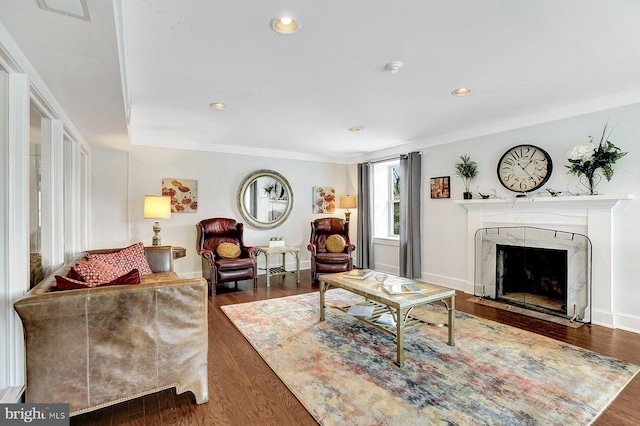 living room with a high end fireplace, dark wood-type flooring, and crown molding