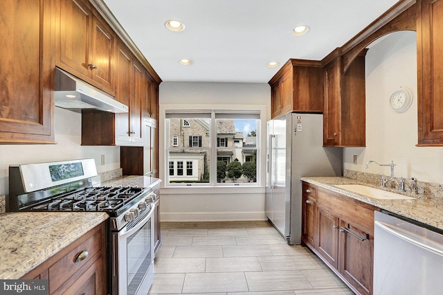 kitchen with appliances with stainless steel finishes, light stone countertops, and sink