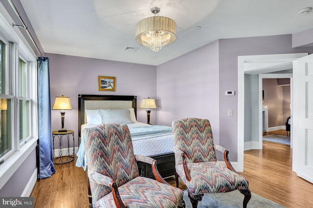 bedroom with an inviting chandelier and light wood-type flooring