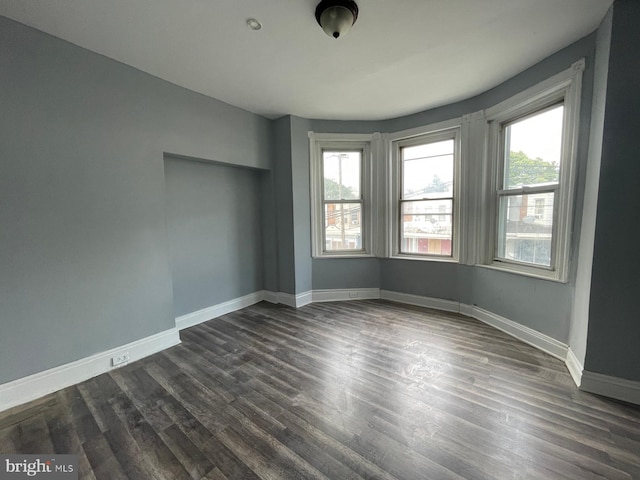 unfurnished room featuring dark wood-style floors and baseboards