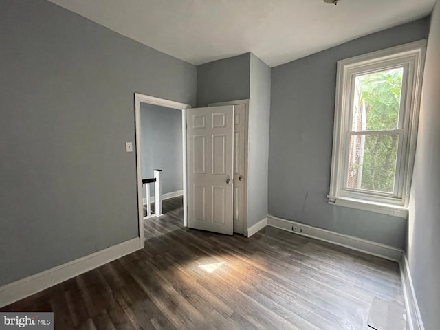 unfurnished bedroom featuring dark wood-type flooring and multiple windows