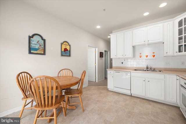 kitchen featuring white dishwasher, light tile patterned floors, sink, decorative backsplash, and white cabinets