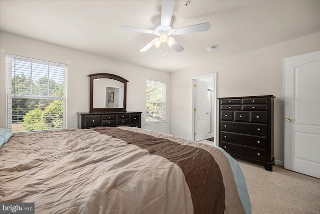 bedroom with ceiling fan, light carpet, and multiple windows