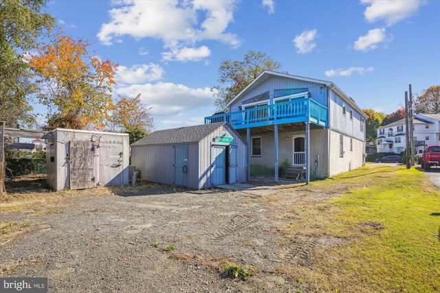 back of house featuring an outbuilding, a shed, a lawn, and a wooden deck