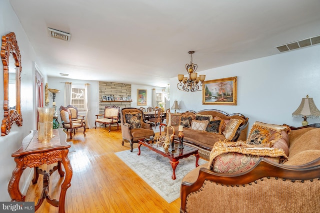 living room featuring light wood-type flooring, a notable chandelier, and brick wall