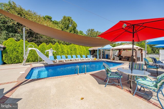 view of swimming pool with a patio and a water slide