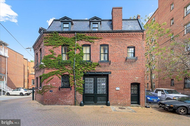 victorian home featuring brick siding, mansard roof, and a high end roof