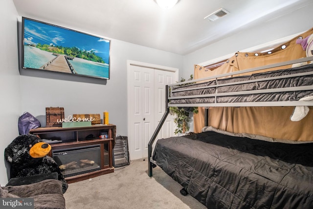 carpeted bedroom with a closet, a fireplace, and visible vents