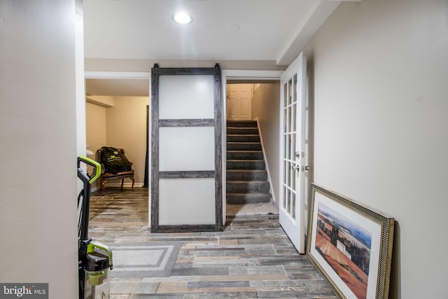 hallway with a barn door, wood-type flooring, and french doors