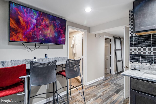 interior space featuring light stone counters, dark wood-style flooring, baseboards, and tasteful backsplash