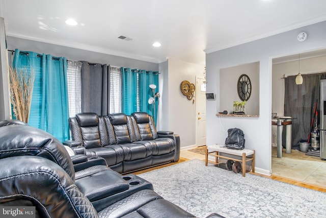 living room featuring baseboards, visible vents, crown molding, and wood finished floors