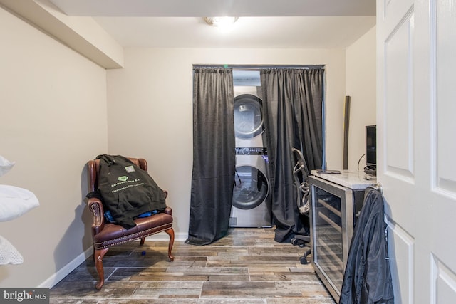 laundry area featuring laundry area, baseboards, stacked washer / dryer, and wood finished floors