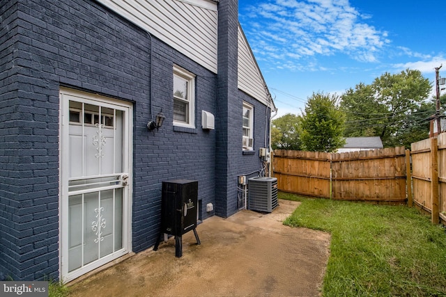 view of home's exterior featuring brick siding, a patio area, fence, and central air condition unit