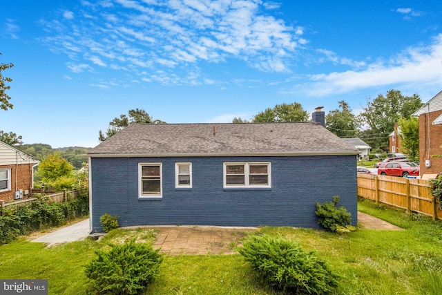 back of property with a yard, brick siding, and fence