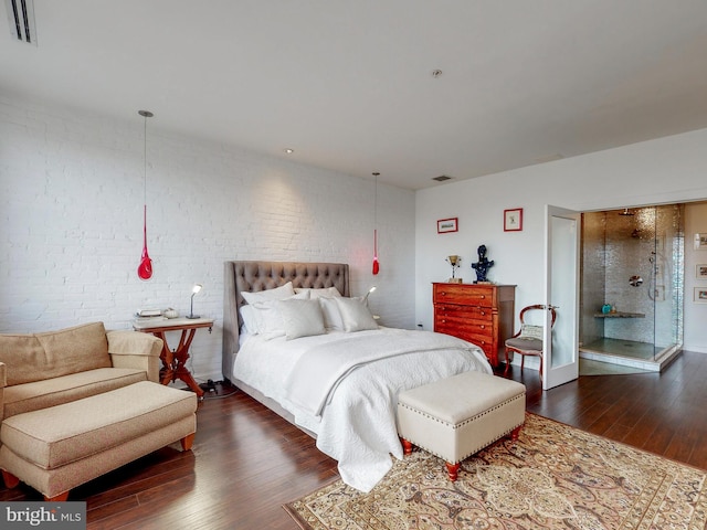 bedroom featuring dark wood-style flooring, visible vents, and brick wall