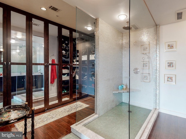 bathroom with a tile shower and wood-type flooring